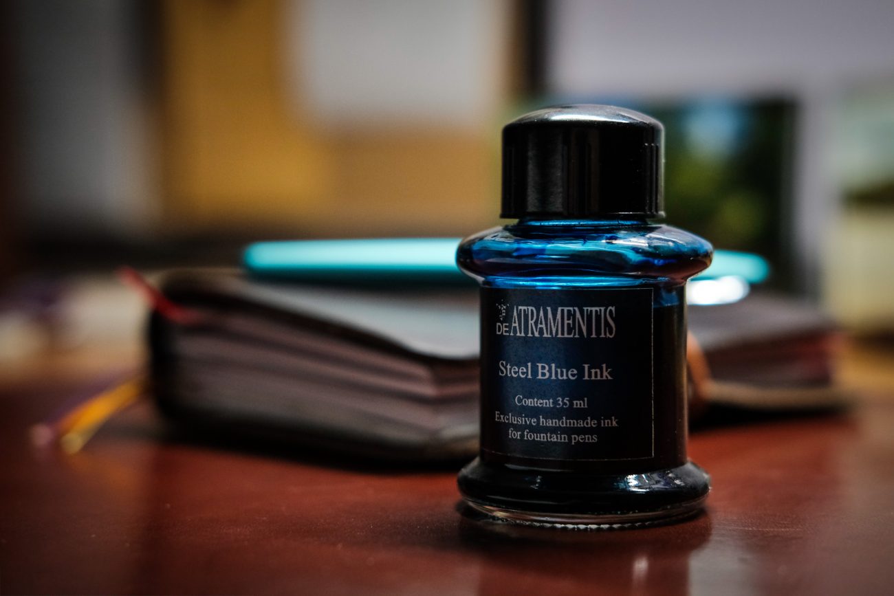 Color photograph of a bottle of DeAtramentis Steel Blue fountain pen ink